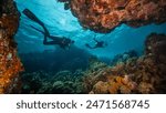 Two Scuba Divers Diving on Tropical Coral Reef with Blue Background and Reef Fish. Red Sea, Egypt.