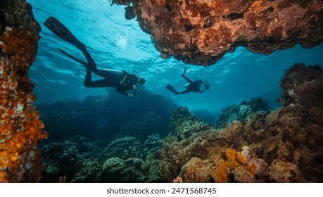 Two Scuba Divers Diving on Tropical Coral Reef with Blue Background and Reef Fish. Red Sea, Egypt.