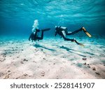 Two scuba divers diving in shallow water. Dahab, South Sinai, Egypt.