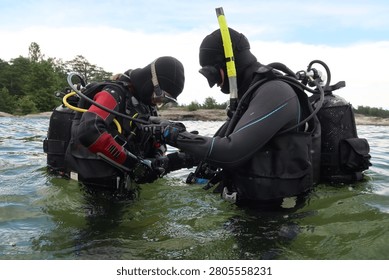 Two Scuba Divers Performing Pre-Dive Buddy Check at Björkviks Brygga Near Stockholm, Sweden