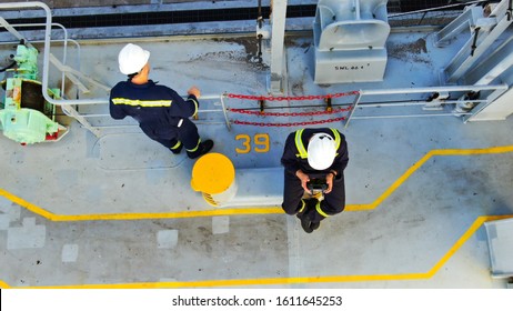 Two Seaman On Deck Of Container Ship Wearing Boiler Suit And Helmets.