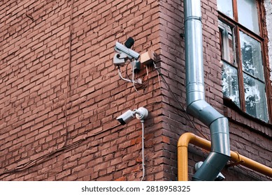 Two security cameras mounted on a red brick wall near a window