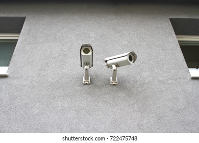 Two security cameras on gray building outdoor