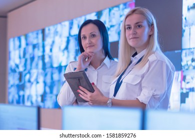 Two security guards working on computers while sitting in the main control room, CCTV surveillance.