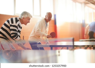 Two senior active men with rackets trying to catch ping pong ball during leisure game - Powered by Shutterstock