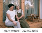 Two senior adult asian woman sisters relax having talk and laughing while sitting on terrace of country house on summer day. Close up