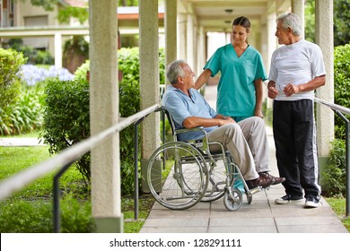 Two senior citizens talking to a nurse in a hospital garden