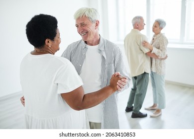 Two Senior Couples Smiling To Each Other Holding Hands While Dancing A Slow Dance In Dance Studio