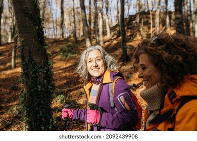 Two Senior Female Friends Hiking Together Through The Forest In Autumn