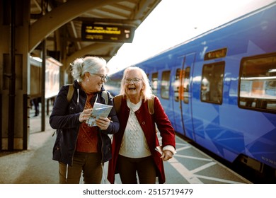 Two senior female friends using map at train station - Powered by Shutterstock