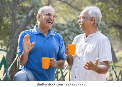 Two senior friends having fun raising a toast with coffee cups at park - Powered by Shutterstock