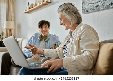 Two senior ladies enjoying technology on a couch.