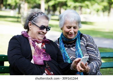 two senior ladies having fun with the technology of smartphone - Powered by Shutterstock