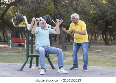 Two Senior Man Having Fun While Exercising In Open Air Gym At Park
