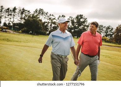 Two senior man playing golf are walking to the next hole. Professional golfers walking and talking on the golf course.