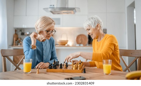 two senior mature women caucasian female woman friends or sisters play leisure chess board game at home have fun spend time together at home bright photo copy space - Powered by Shutterstock