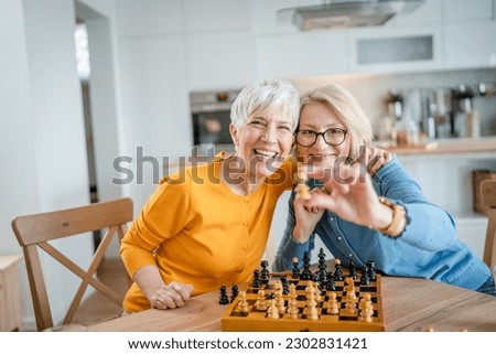 two senior mature women caucasian female woman friends or sisters play leisure chess board game at home have fun spend time together at home bright photo copy space
