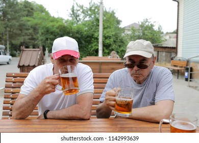 Two Senior Men Drinking Beer In Outdoor Cafe