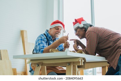 Two senior old retired men wearing Santa hat, sitting and making DIY wooden decoration together as hobby and freetime, celebrating New year, Christmas Party after work, smiling with happiness at home - Powered by Shutterstock