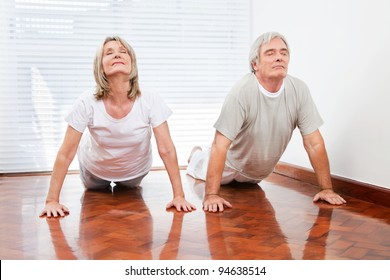 Two senior people doing yoga exercise Bhujangasana in gym