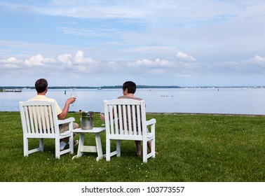 Two Senior People In Patio Chairs Drinking Champagne By Chesapeake Bay