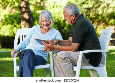 Two senior people sitting with a tablet PC in a nature park - Powered by Shutterstock