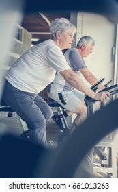 Two Senior People Working Out On Elliptical Machine. Seniors Workout In Gym.