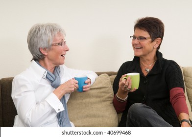 Two Senior Women Drinking Coffee, Chatting And Having A Good Time Together As Girl-friends.