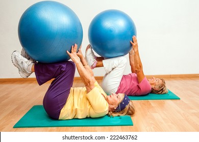 Two Senior Women Exercising Muscles With Swiss Balls In Health Club.