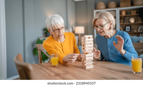 two senior women female woman friends or family sisters play leisure board game at home have fun pensioner grandmother spend time together with their mature daughter - Powered by Shutterstock