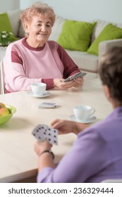 Two Senior Women Playing Cards In Lounge