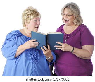 Two Senior Women Singing From The Same Book.  One Looks At The Music Happily While The Other Scowls As She Looks At Her.  On A White Background.