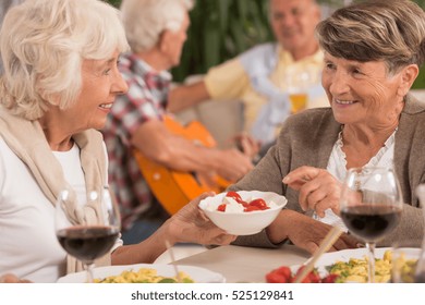 Two Senior Women Talking And Drinking Wine During Dinner