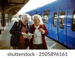 Two senior women at train station with map