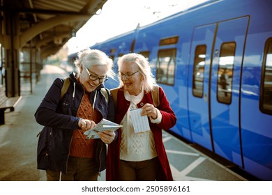 Two senior women at train station with map - Powered by Shutterstock