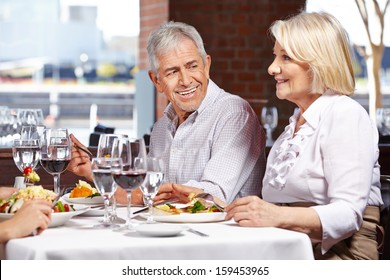 Two Seniors Eating Out In Restaurant With Their Children