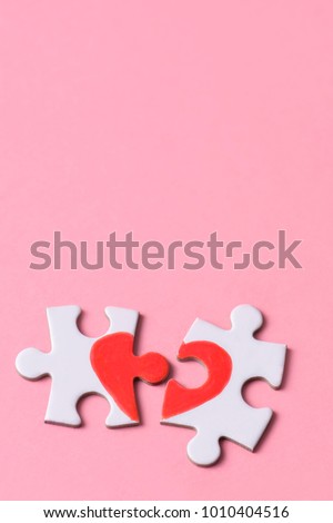 two separated pieces of a puzzle which together form on a pink background with a blank space on top, depicting the idea of rupture or cooperation