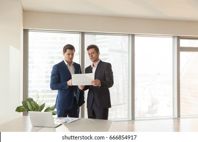 Two serious businessmen discussing building plan, investment adviser offering new project to investor, partners considering construction investment, joint venture business, buying real estate