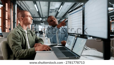 Two IT Service Managers Use Laptops Together Solving Incident Tickets Efficiently.