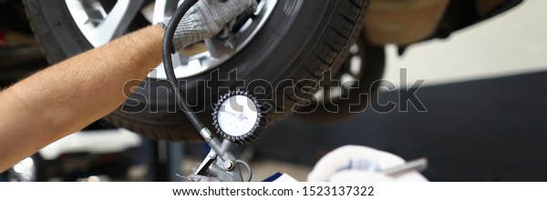 Two serviceman inspects a pre-sale vehicle\
against background of technical service department. Pressure test\
and seasonal tire change\
concept