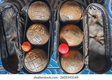 Two set of old rusty Petanque sports equipment in old small bag. Old petanque six balls and small wood jack. Bag with set of balls for petanque game. Rusty balls in boules for competition or as hobby.