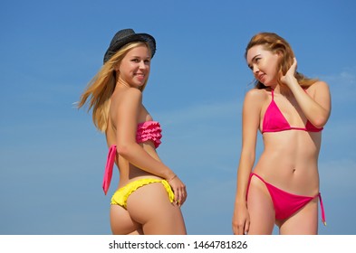 Two sexy girls on the sky background in a swimsuit.