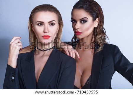 Two sexy models with perfect body, strong make up and red lips looking at the