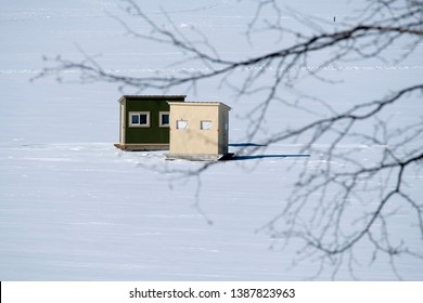 Two shacks used for ice fishing on a frozen snow covered lake in New England. It is a popular winter sport in rural communities in New England. - Powered by Shutterstock