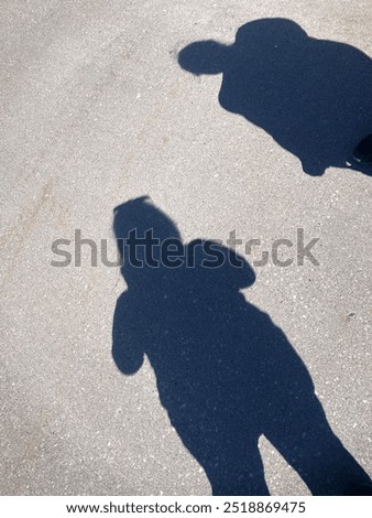 Two Shadows Looking Down at the Pavement