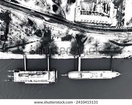 Two ships anchored by the river near park - black and white. Aerial top down view.