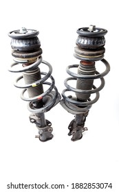 Two Shock Absorber Struts With Black Springs After Being Used On A Car During Replacement And Repair On A White Isolated Background. Used Spare Parts. Auto Parts Catalog.