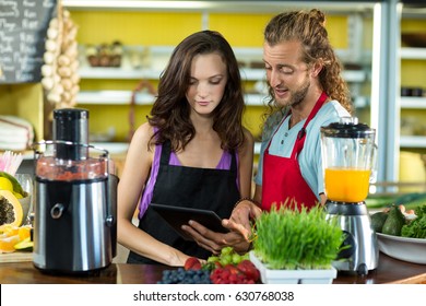 Two shop assistants discussing with digital tablet at health grocery shop - Powered by Shutterstock