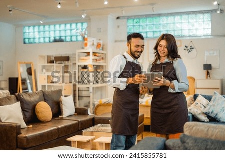 two shop owners using a tablet together standing in a furniture shop