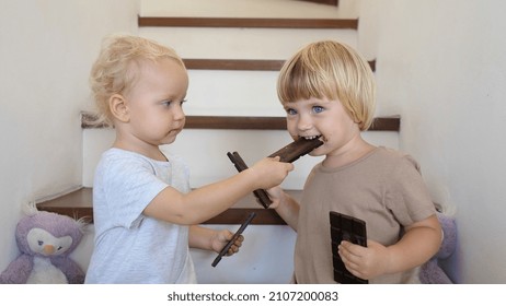 Two Siblings Sharing And Feeding Each Other With Chocolate Bars Enjoying Childhood Freedom And Family Fun